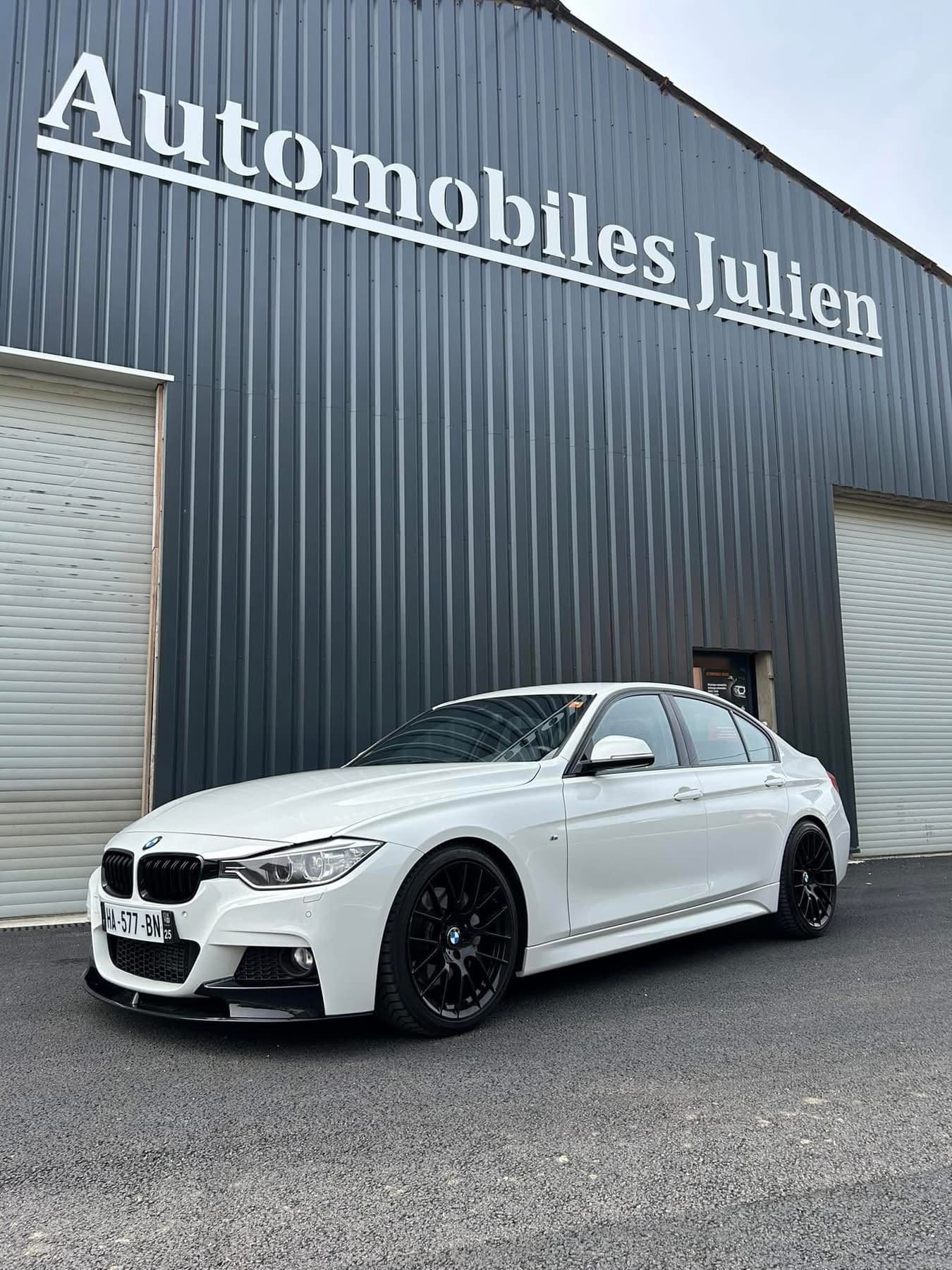 BMW Série 3 blanche devant le garage