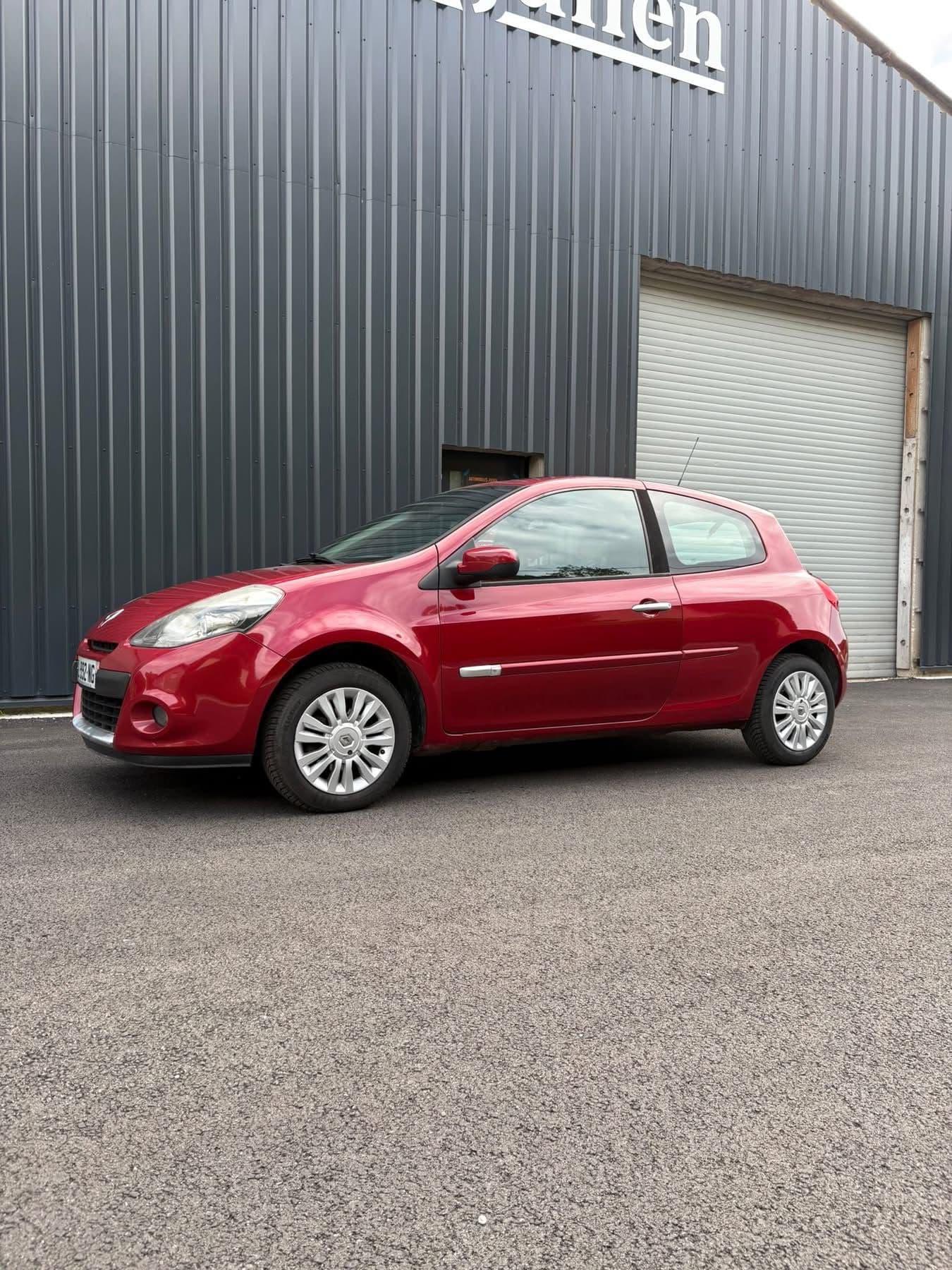 Renault Clio rouge devant le garage
