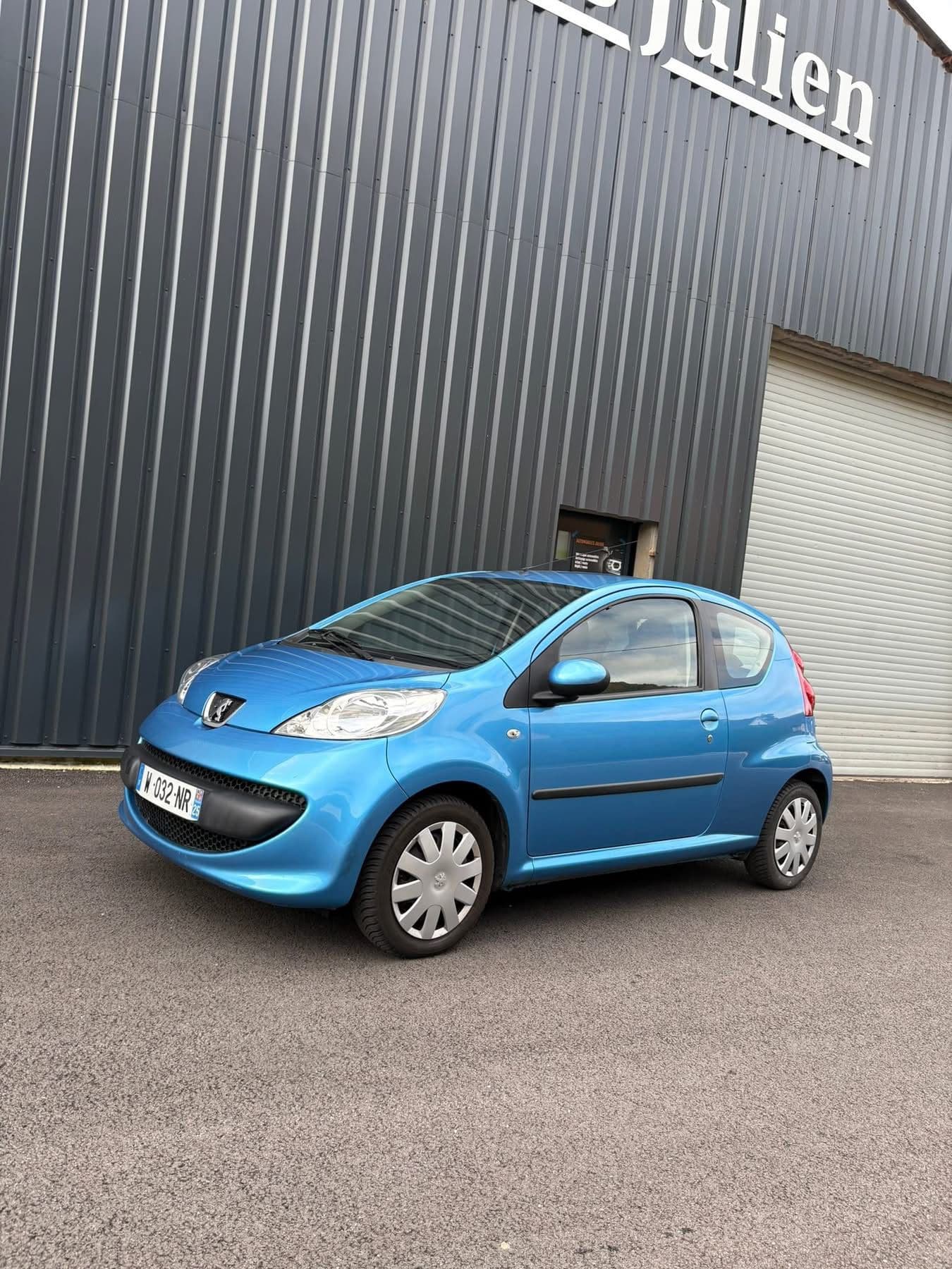 Peugeot 107 bleue devant le garage
